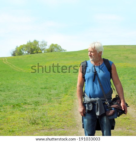 Old handsome gray-haired man photographer photographing in nature