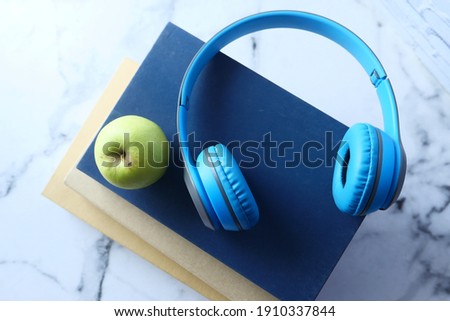 Audio book concept. Headphones and book over black background 