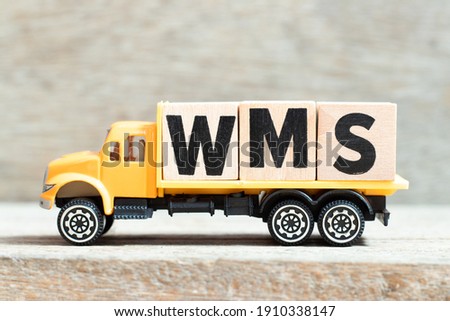 Toy truck hold alphabet letter block in word WMS (Abbreviation of warehouse management system) on wood background Royalty-Free Stock Photo #1910338147