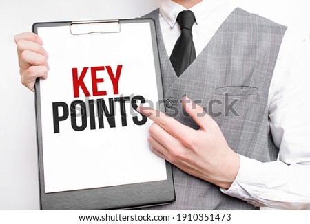 KEY POINTS inscription on a notebook in the hands of a businessman on a gray background, a man points with a finger to the text
