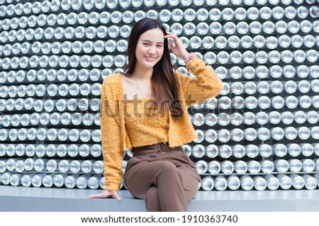 Asian beautiful woman with black long hair in yellow coat is pretty smiling. abstract background