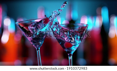 Closeup of splashing martini cocktails in cheers gesture. Bar on background, free space for text Royalty-Free Stock Photo #1910372983