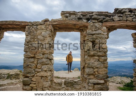 Outdoor photographer looking at a landscape from a height through a truncated glass ruin wall