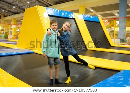 Happy smiling 11 years old kids jumping on trampoline indoors in entertainment center. Active children leisure, jumping and playing on trampoline in sport center. Amusement park. Sport activity. Royalty-Free Stock Photo #1910397580