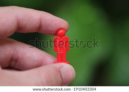 Red mannequin held by hand, by the key in the lead of the game.