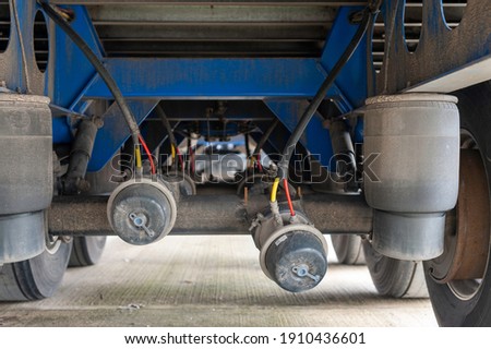 Underneath View of a Semi Trailer showing the Three Axles and Air bags and Brake Chambers with one of the Offside Rear Broken off the Axle with Shallow focus.