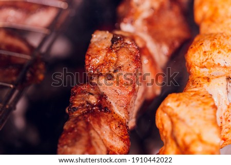Grilled kebab cooking on metal skewer. Roasted meat cooked at barbecue. BBQ fresh beef meat chop slices. Traditional eastern dish, shish kebab. Grill on charcoal and flame, picnic, street food.