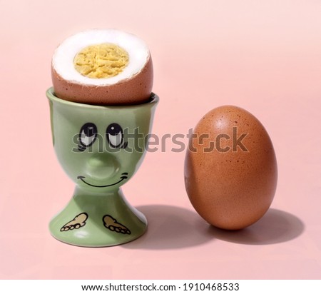 a smart egg with a yolk in the form of a brain and in a stand next to its blunt egg-brother
