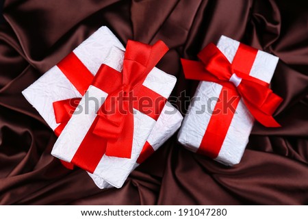 Beautiful gifts with red ribbons on silk background