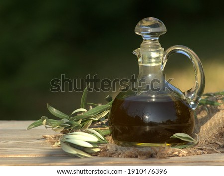 Olive oil in the bottle and olive branch on the table.                      
Oil background. 
 Royalty-Free Stock Photo #1910476396