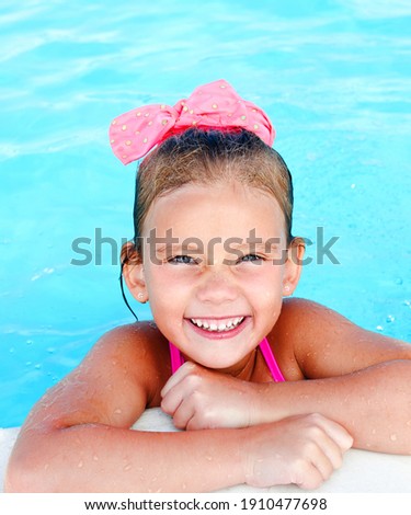 Cute smiling little girl in swimming pool on summer vacation  