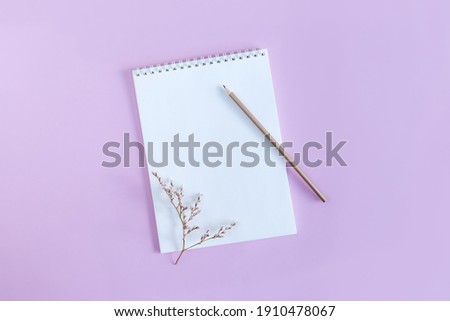 Notebook with blank page and pencil on a violet pastel background. Flat lay. Place for text. 