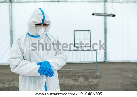 Unrecognizable nurse portrait with copy space. Man with personal protective equipments and suit preparing to take a swab. Drive-Thru station for covid-19 screening test.