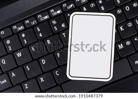 Empty blank logo frame, text frame, rectangle sticker, label, paper note, sign laying on a laptop keyboard, copy space, logo or text space. Simple technology IT branding, mockup, smart tech template