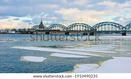 riga,panorama of the city, in the photo the city and the railway bridge,in the foreground the river and ice floes