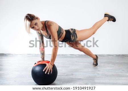 Fit young blonde woman doing exercise with medicine ball in gym.