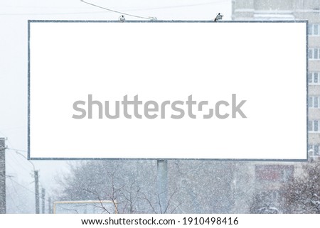 Blank billboard for advertising, announcements, information, campaigning, etc., in winter during snowfall. Mock up.