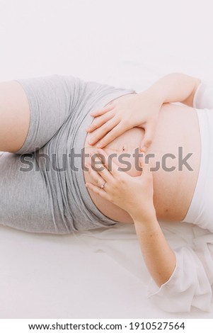 A Young beautiful Asian woman standing in bedroom. mom is love to holding her big belly with two hands. isolated and white background picture with film grain effect