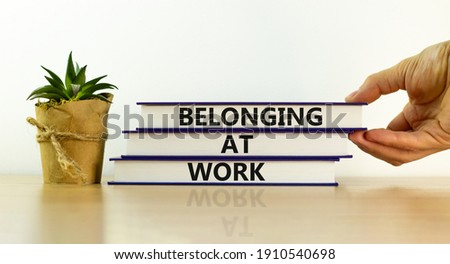 Belonging at work symbol. Books with words 'Belonging at work' on beautiful white background. Businessman hand. Business, belonging at work concept. Copy space.