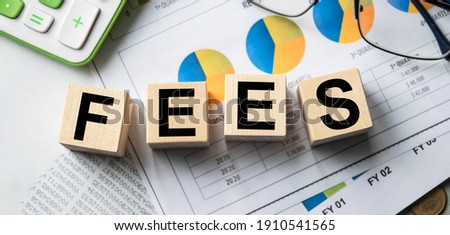 The inscription on the cubes, the word FEES on the cubes of wooden texture. View from above. Desktop with documents. An inscription on a financial, business or economic theme.