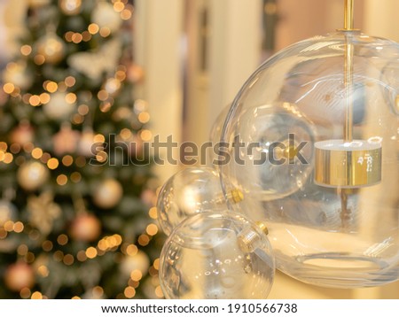 The group glass lamps made of steel with LED bulb inside are hanging on the ceiling in the office. Christmas tree on the background. Concept of interior decoration for the new year.