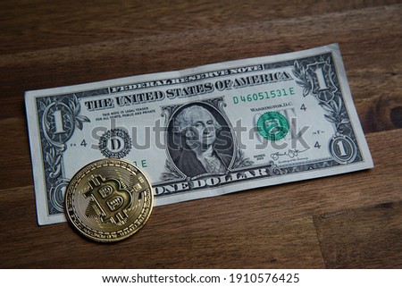 Pile of American one dollar cash. Next to it are several gold bitcoin digital cryptocurrency coins. Bank image and photo background.