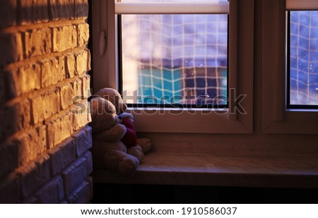 
two teddy bears holding a red heart. Teddy bears sit on the windowsill and look out the window. Romantic photo concept for Valentine's Day