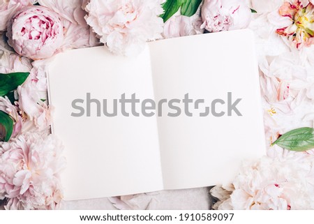 Frame made of pink peony flowers and open notebook for writing your dreams or manifistations. Feminine flower composition. Flat lay, top view.