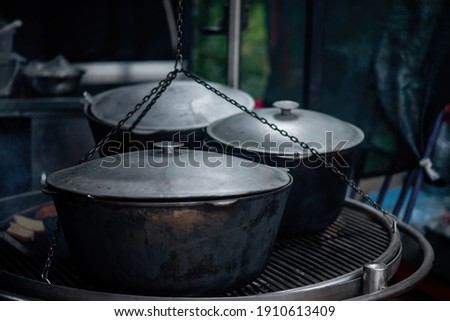 Large gray iron aluminum cauldrons on the grill, in which a campfire is prepared for takeaway at a festival, weekend getaway in the forest.