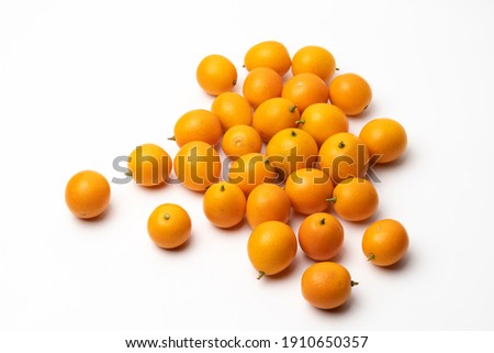 Multiple small kumquats on a pure white background
