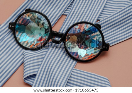 designer glasses with kaleidoscope lenses on pink background with textile ribbon