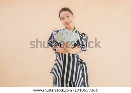 Portrait beautiful young asian woman with cash and money on brown background