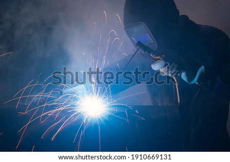 Industry welder working with electrode at arc welding in construction site.Welders working at the factory made metal parts in a protective suit. Royalty-Free Stock Photo #1910669131
