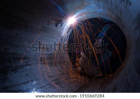 Industry welder working with electrode at arc welding in construction site.Welders working at the factory made metal parts in a protective suit. Royalty-Free Stock Photo #1910669284