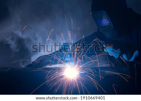 Industry welder working with electrode at arc welding in construction site.Welders working at the factory made metal parts in a protective suit. Royalty-Free Stock Photo #1910669401