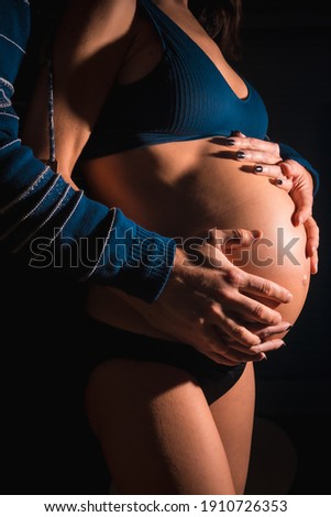 Young Caucasian pregnant woman about to give birth. With the hands of her father and her mother on the baby's belly. In some studio photos