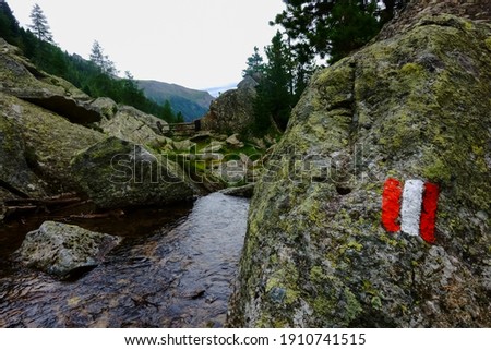 sign from austria on a rock next to a mountain stream while hiking