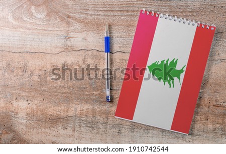 Notepad with Lebanon flag, pen on wooden background, study concept
