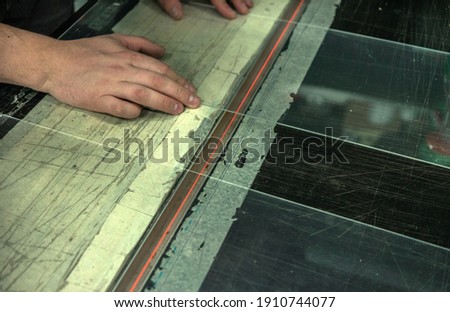 Hands hold transparent Plexiglass. Bending plastic on a heated metal string. Production of outdoor advertising.