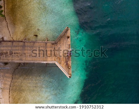 Top down aerial view. A loving couple are sitting on a wooden bridge, a pier. Sunny day, clear water, mountain lake. The concept of romance, outdoor recreation. travel. (Bohinjsko jezero) Slovenija