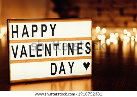 Stylish text frame lightbox with the inscription happy Valentine's day. Dark dramatic background with bokeh balls.