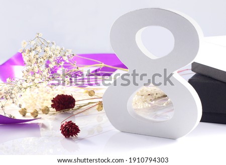 Women's day, number 8 in wood, with preserved flowers and violet ribbon and boxes in the background.On light background