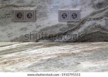 Beige marble table with electric outlets on stone wall texture background, suitable for advertise product display presentation backdrop and mock up