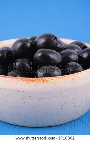 bowl full of black olives on blue background