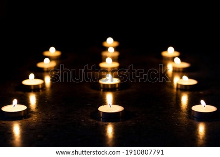 selective focus on candles arranged in rows on reflecting surface and black background