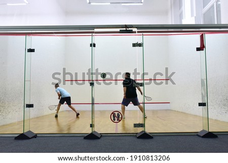 Squash player in action reaching on squash court. Squash Players on Tournament. Sports equipment and sportswear for playing squash.  Soft focus Royalty-Free Stock Photo #1910813206