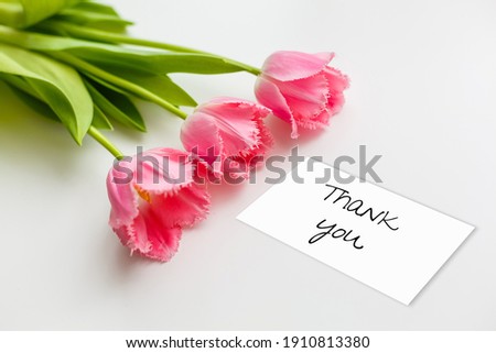 Thank you card, gift box and tulip bouquet on white