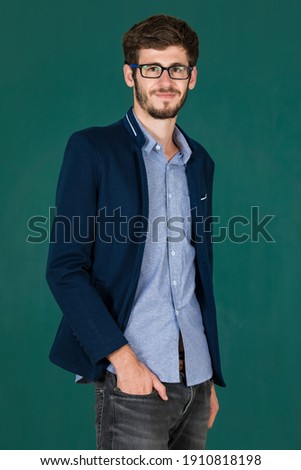 Studio shot portrait of a cute and elegant executive man wearing eyesglasses in blue suit jacket standing and smile to the camera with self-confident on green screen.