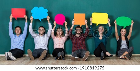 Group of six business people team sittiing together and holding colorful and different shapes of speech bubbles Royalty-Free Stock Photo #1910819275
