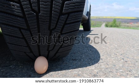 The photo shows an image of a car tire and a chicken egg